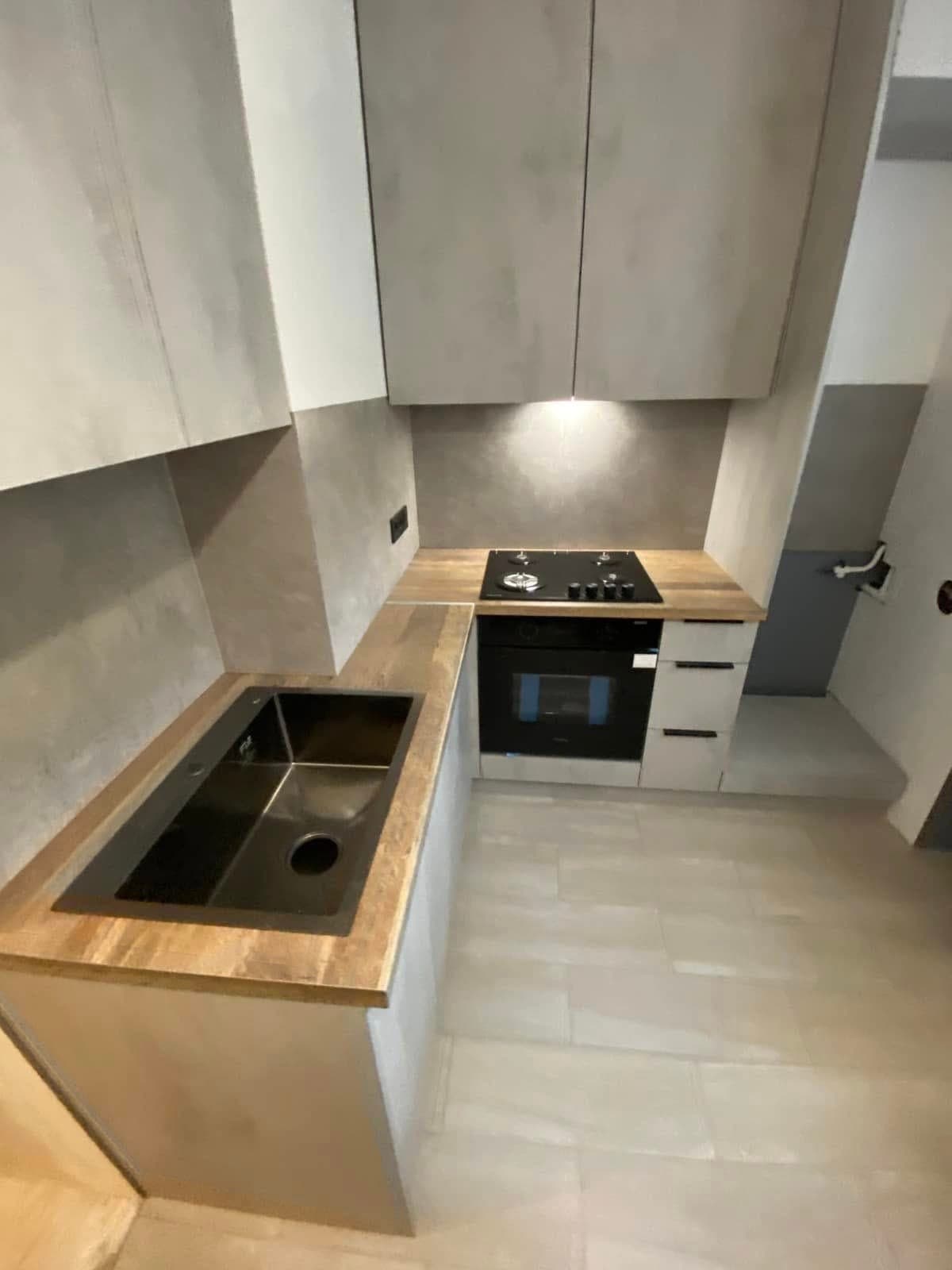 Ближчий план чорної мийки та варильної панелі на деревній стільниці